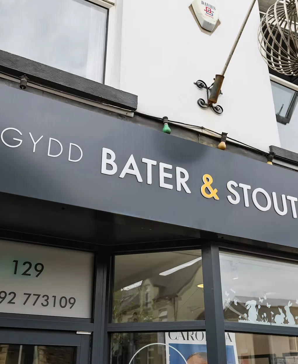 A close crop of the Bater and Stout fascia and door, with 129 and the phone number on the window decals