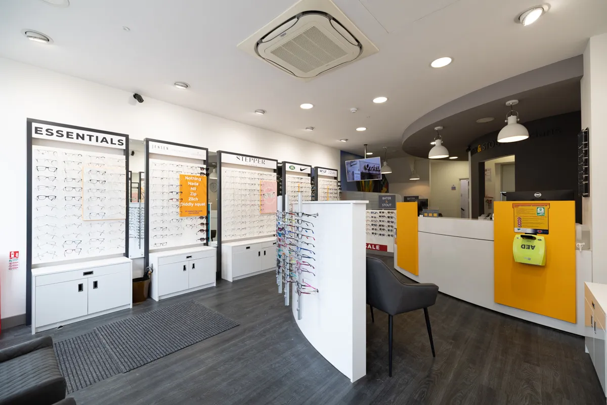 The Bater and Stout shop floor interior, frame walls labelled Essentials, Jessica, Stepper, Nike, Wolf, with the charcoal counter and amber AED panel